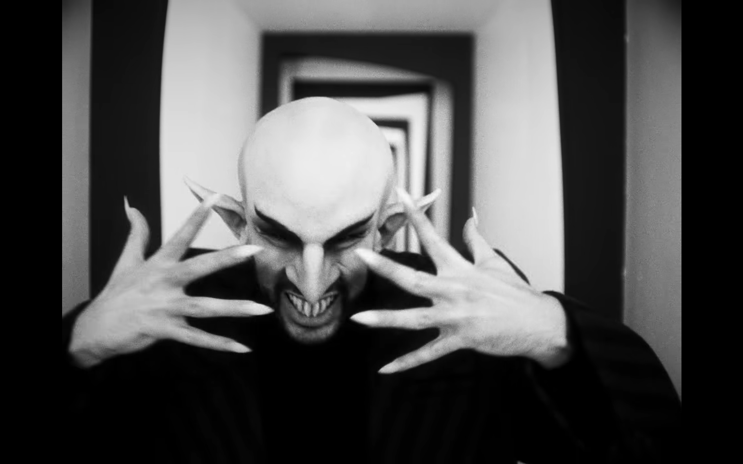 BBBaticano.png: Frame of Bad Bunny dressed as Nosferatu and wearing long nails in his music video “BATICANO.” Via Bad Bunny’s YouTube.