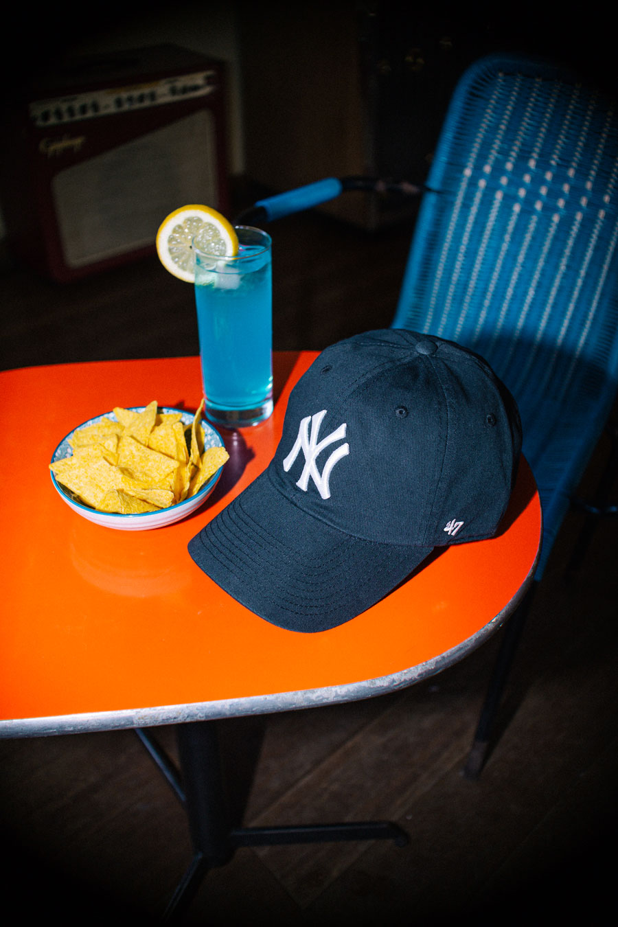 Blue curved visor cap with large NY Yankees logo resting on cocktail bar table