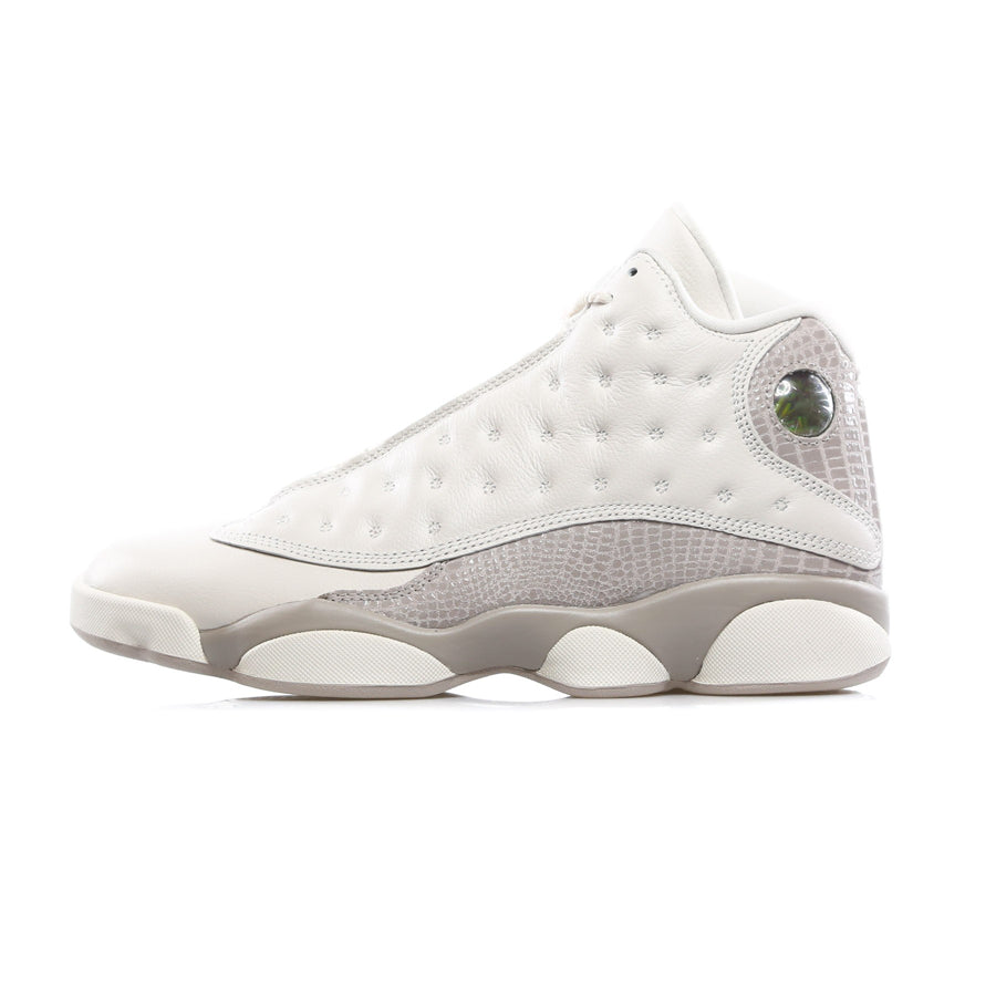 Nike Air Jordan 13 retro basketball sneaker in the white and gray colorway with python leather inserts and hologram with Jordan logo on the high neck