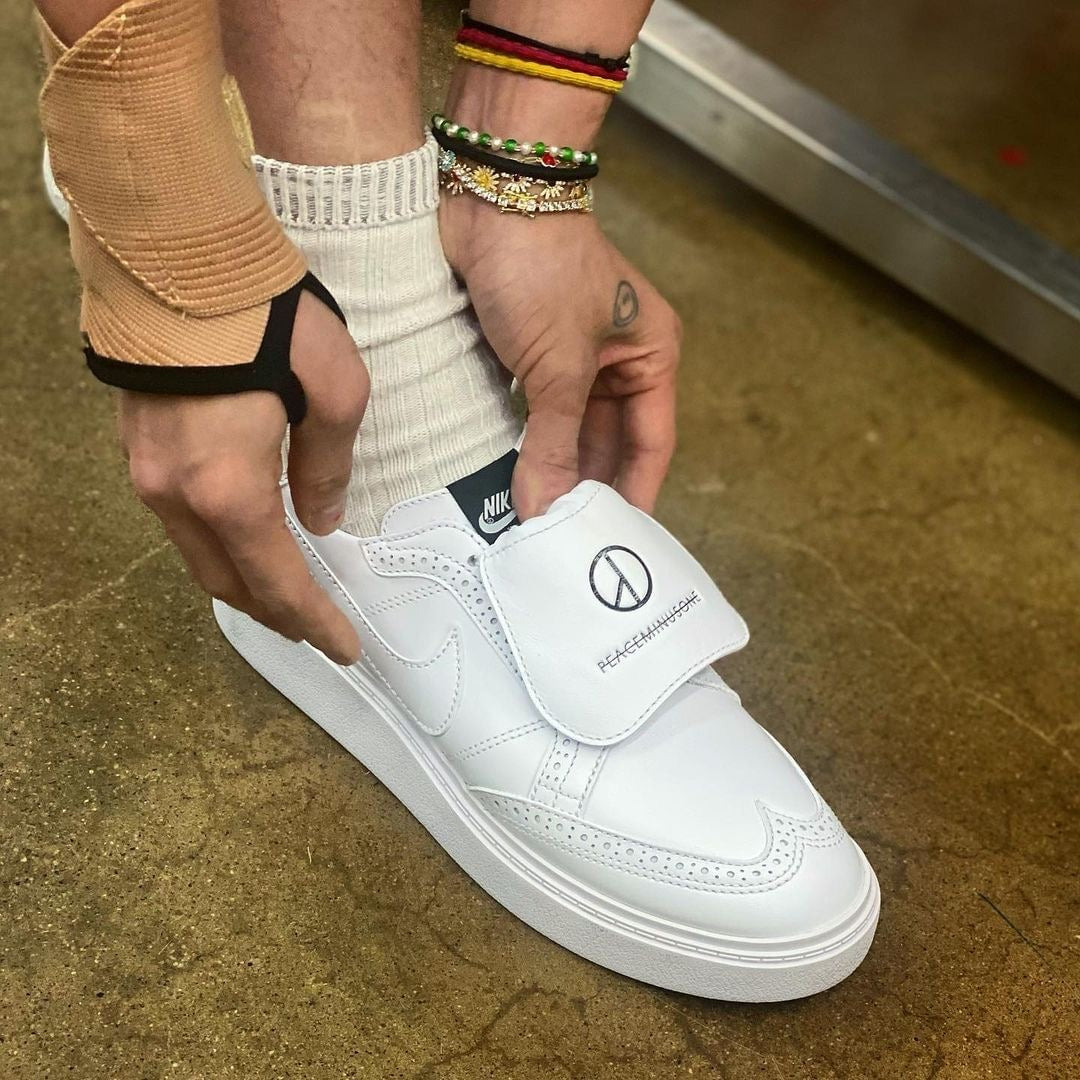 Sneaker elegante bianca Peaceminusone x Nike Kwondo 1 indossata con copri lacci con logo impresso