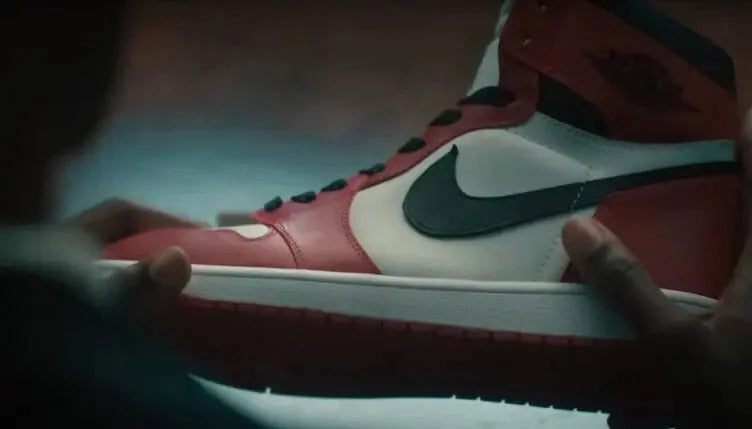 Scene from the film AIR: the story of the great leap in which the Nike designer holds the first Air Jordan 1 Chicago in his hand in the iconic white red black colorway