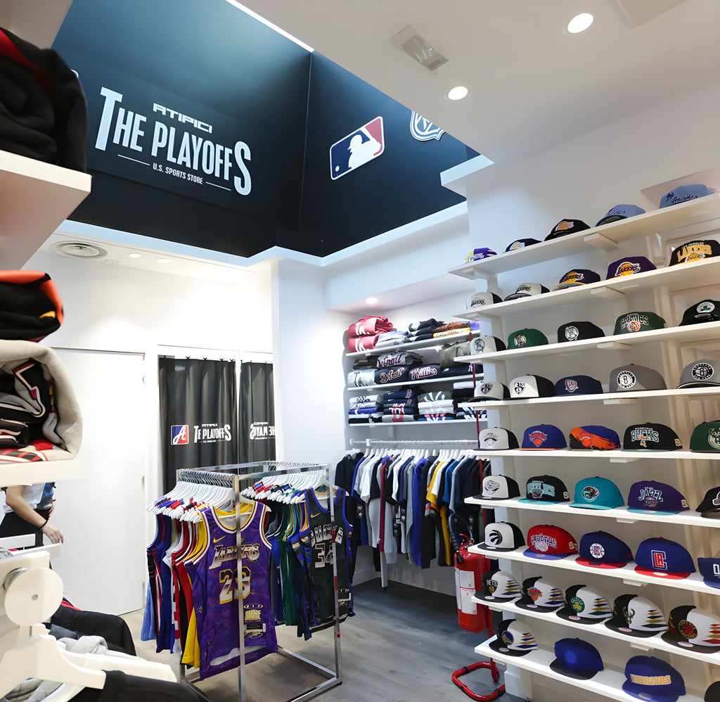Selection of clothing, accessories and peaked caps from the best NBA, NFL, MLB and NHL teams displayed in The Playoffs Corner, area of ​​the Atipici Shop Milano Corso Buenos Aires 25 dedicated to US Sports fan gear
