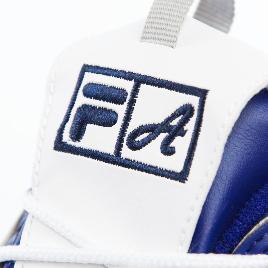 Dettaglio della linguetta delle sneakers Fila x Atipici Disruptor con iniziali F. di Fila e A. di Atipici ricamate in filo premium blu