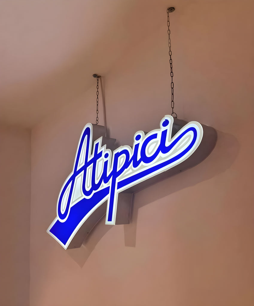 3D luminous sign with the Atipici logo positioned in the Atipici Shop Bologna store in via Clavature 14