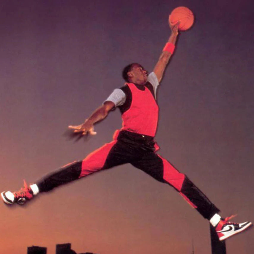 foto leggendaria di Michael Jordan che schiaccia a canestro nell'iconica posa a gambe larghe e braccio teso diventato il logo Jumpman del brand Jordan