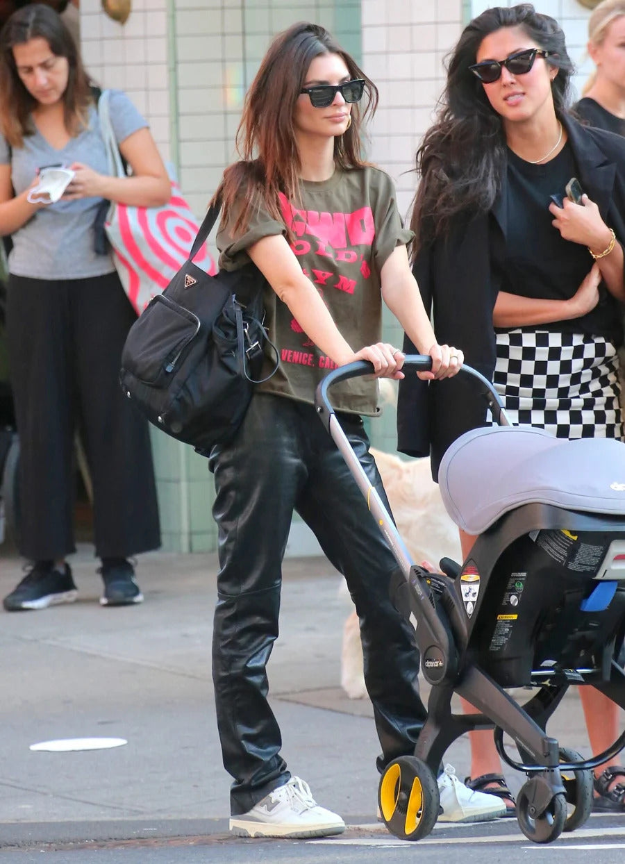 Emily Ratajkowski wears gray New Balance 550 skate shoes while carrying a stroller