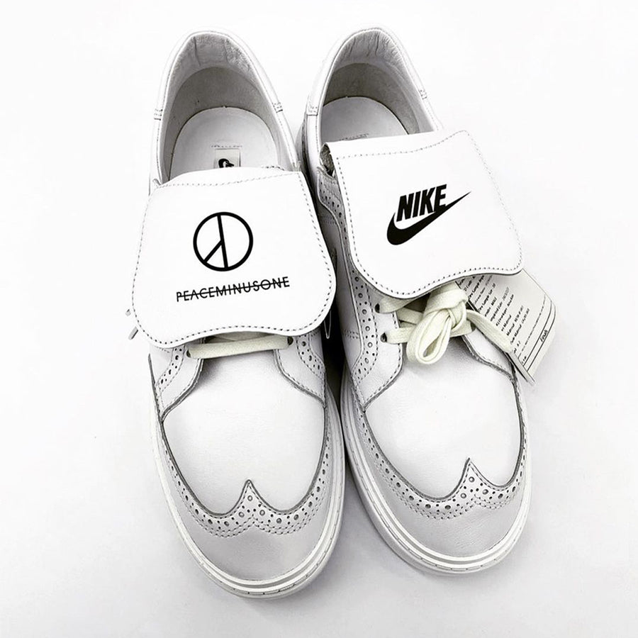 Pair of elegant Peaceminusone x Nike Kwondo 1 white colorway sneakers with Parisian stitching on the toe of the upper and lace covers branded Peaceminusone and Nike Swoosh