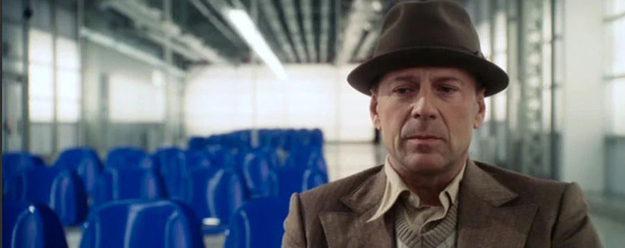 scene from the film Slevin, Criminal Pact with Bruce Willis in a waiting room dressed in a raincoat and hat