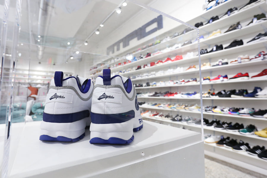 Pair of Fila x Atipici Disruptor The Blueprint collectible sneakers displayed in the display case inside the Atipici Shop Torino in via Pietro Micca 2