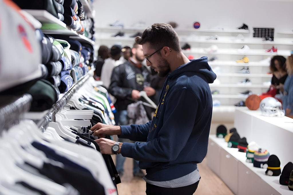 Boy dressed in sportswear with hoodie looks at original t-shirts and jackets of the best NBA, NFL, MLB and NHL teams displayed during the inauguration of The Playoffs Turin American sports fan shop in via Roma 220