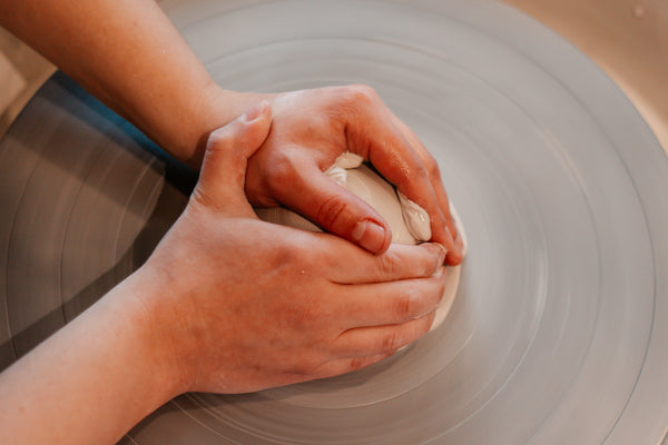 Deux mains sur une boule d'argile pour centrer