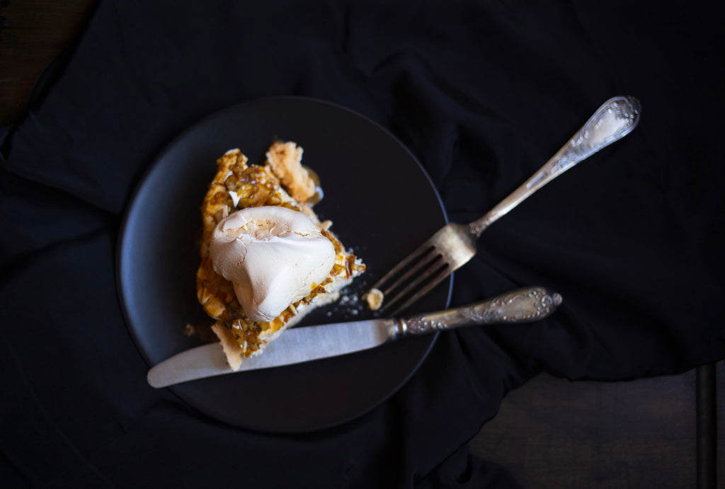 a piece of pavlova cake with walnuts and coffee sauce on a black background top view