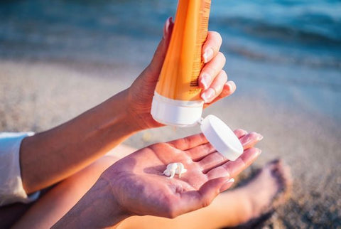 crème solaire dans une main avec fond plage