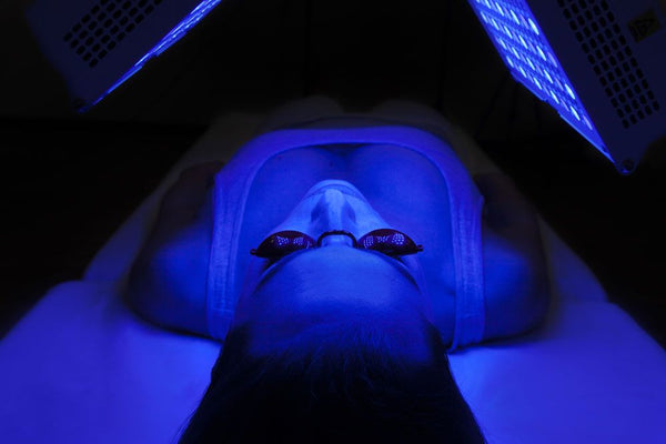 femme couché dans le noir en séance de luminothérapie bleue dans un institut de beauté