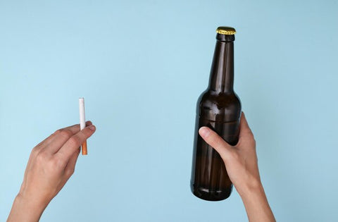 cigarette et bouteille de bière dans deux mains avec fond bleu