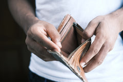 corps d'un homme avec t shirt blanc  regardant dans la poche de son porte monnaie vide