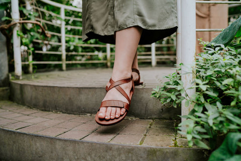 Eine Frau in Barfuß-Sandalen von Ahinsa shoes geht die Treppe hinunter.