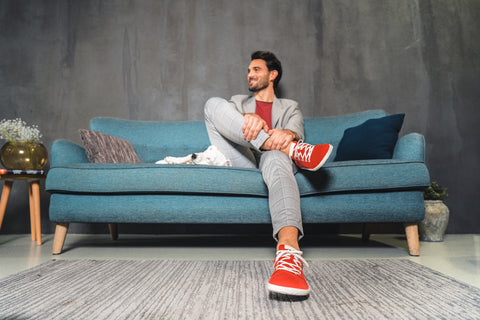 Mann sitzt auf dem Sofa, trägt einen Freizeitanzug und Hanf-Sneaker