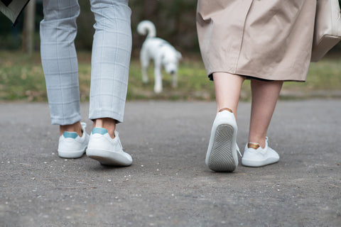 Ein Mann und eine Frau gehen durch die Stadt, an ihren Füßen tragen sie Barfuß-Sneaker von Ahinsa Shoes.