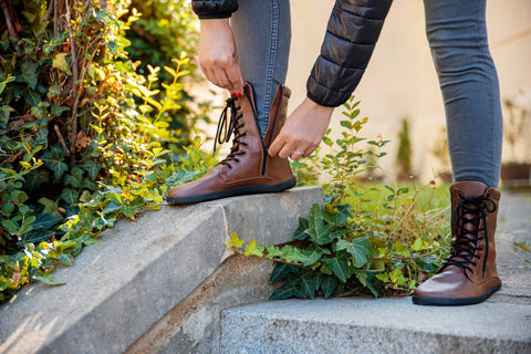 Eine Frau zieht den Reißverschluss ihrer winterlichen Barfußschuhen von Ahinsa shoes hoch.