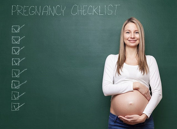 1.Pregnant woman holding bump in front of a chalk board with pregnancy checklist