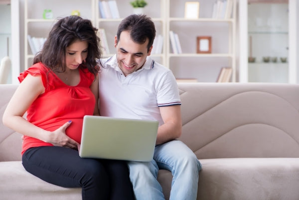 1. Pregnant woman and partner looking at a laptop together