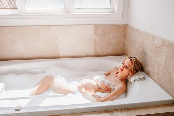 2. Pregnant woman in a soapy bath holding her baby bump