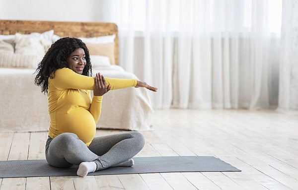 Pregnant lady sat warming up on a yoga mat