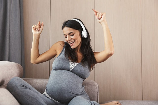 3 pregnant woman dancing whilst sitting down listening to headphones