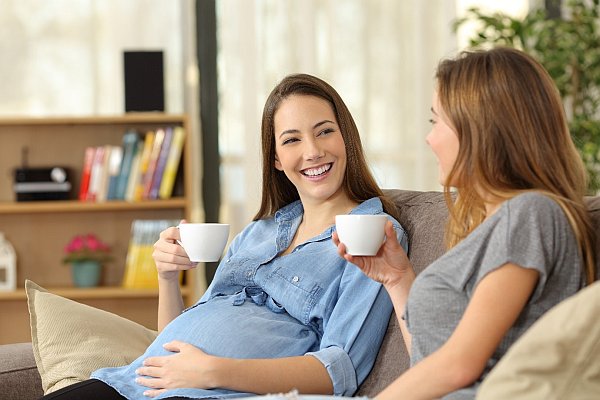 Two pregnany women smilingand not thinking about body image post pregnancy
