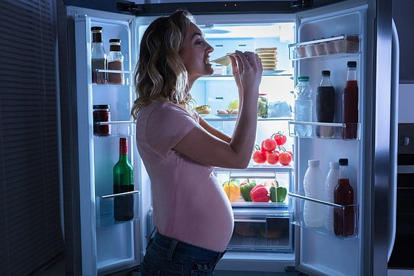 4. pregnant woman eating in front of an open fridge