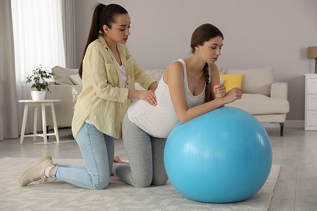 4. pregnant woman leaning on gym ball having back massage