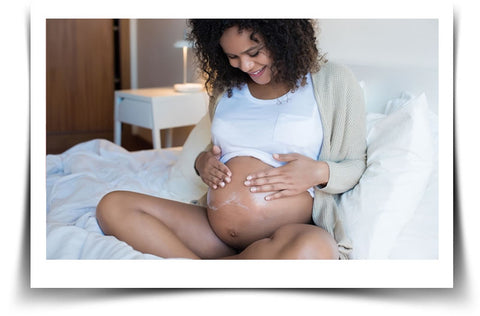 Woman Holding Pregnant Bump in Bed - Stretch Mark Prevention system