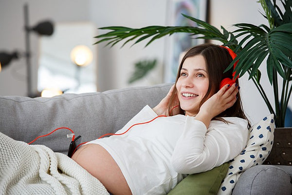 5 smiling pregnant woman listening to music from her phone