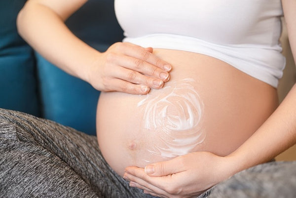 pregnant woman massages tummy with cream