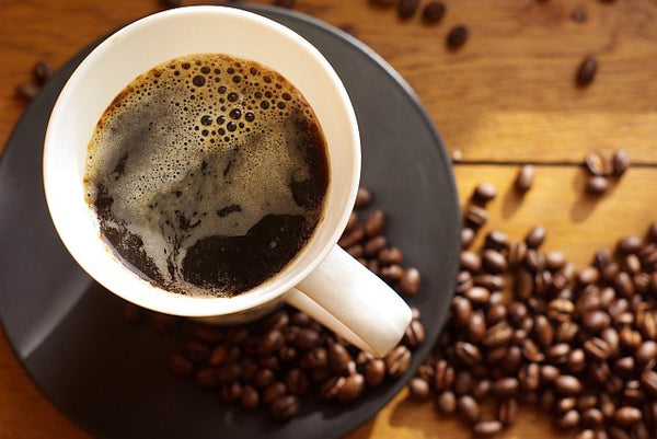 Black coffee surrounded by coffee beans