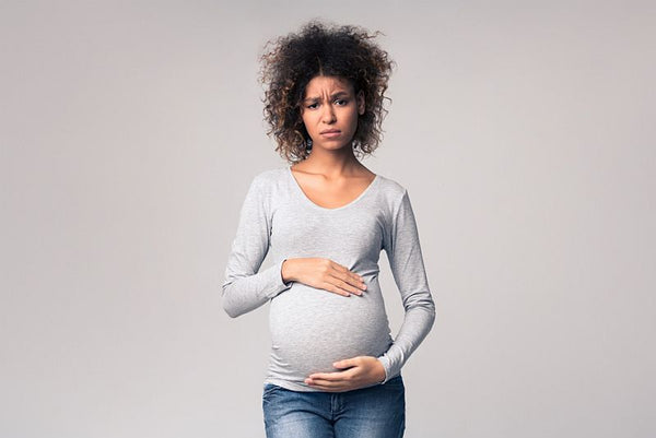 Stressed pregnant woman holding baby bump