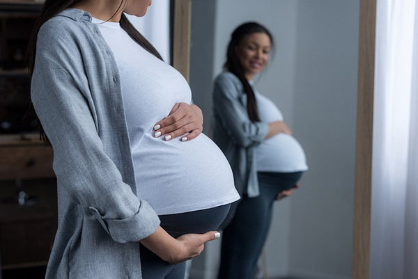 Pregnant woman looking in a mirror at her bump