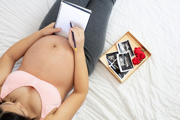 pregnant woman writing notes with box a baby scan images