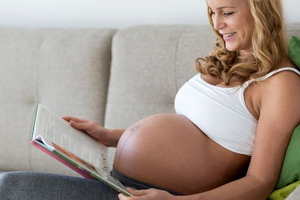 relaxed pregnant woman with no stretch marks reading