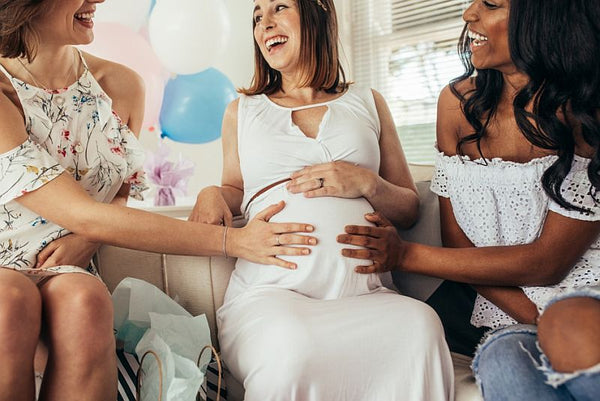 pregnant woman laughs with friends at baby shower