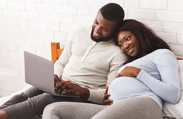 Pregnant black woman and partner looking at laptop
