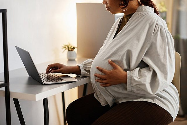 heavily pregnant woman working on a laptop