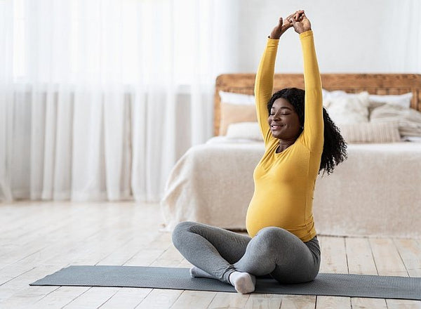 pregnant lady stretching on a yoga mat