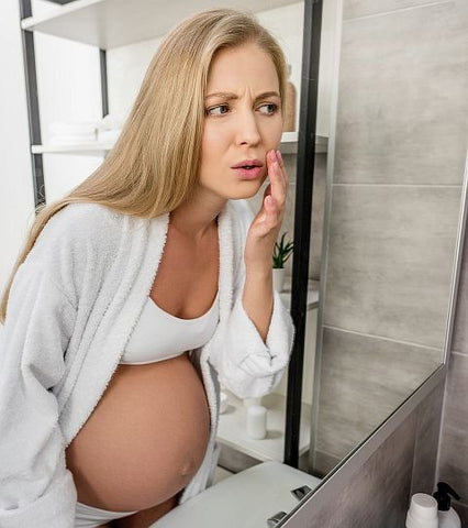 pregnant woman looking in a mirror at her face