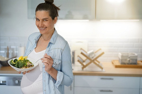 pregnant woman with fresh healthy food in kitchen