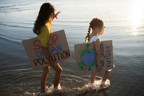 dzieci idące plażą z plakatami na dzień ziemi
