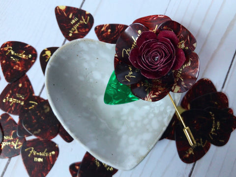 Boutonniere made out of guitar picks on heart shaped bowl with picks in the background.