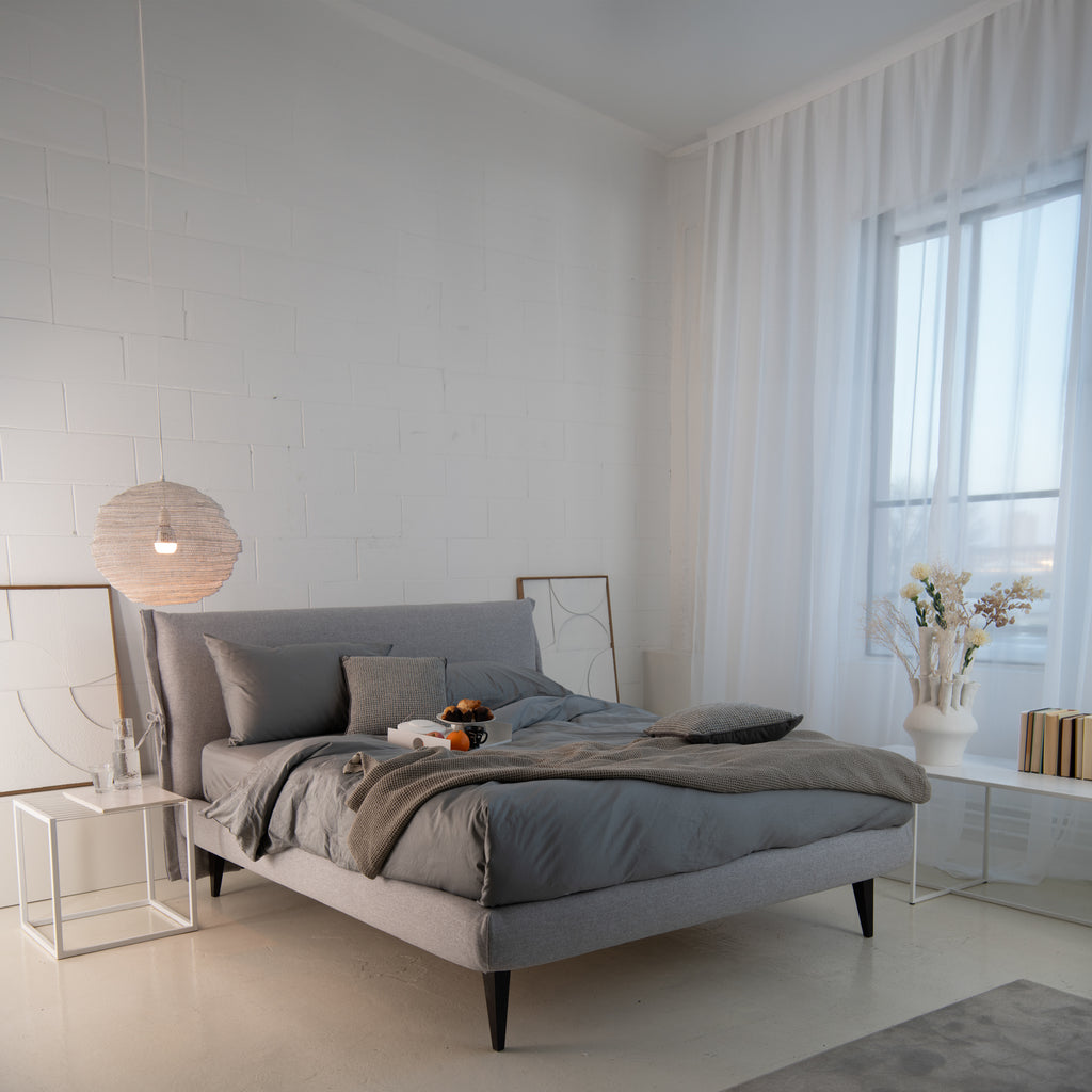 Camera da letto moderna e luminosa con letto, materasso e cuscini Dorelan, completo di biancheria grigia.