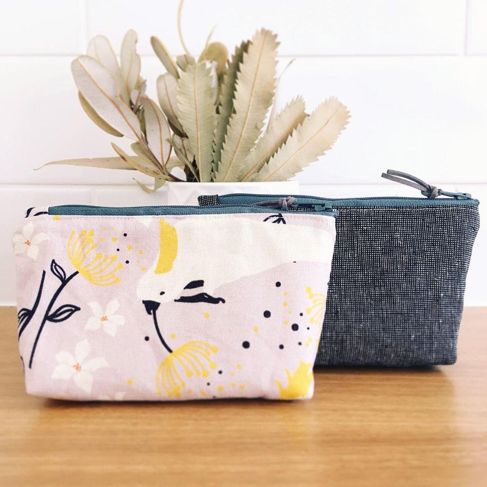 A pair of Banksia and Bloom zipper pouches; one in a grey linen and the other in a cockatoo and gum blossom print